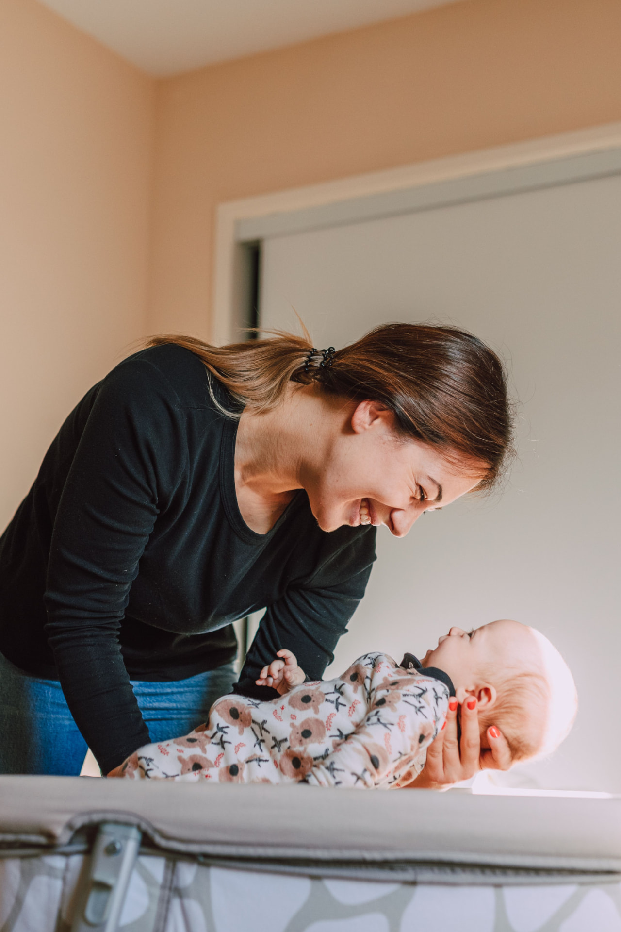 A mother smiling down at her baby during a gentle changing-table moment